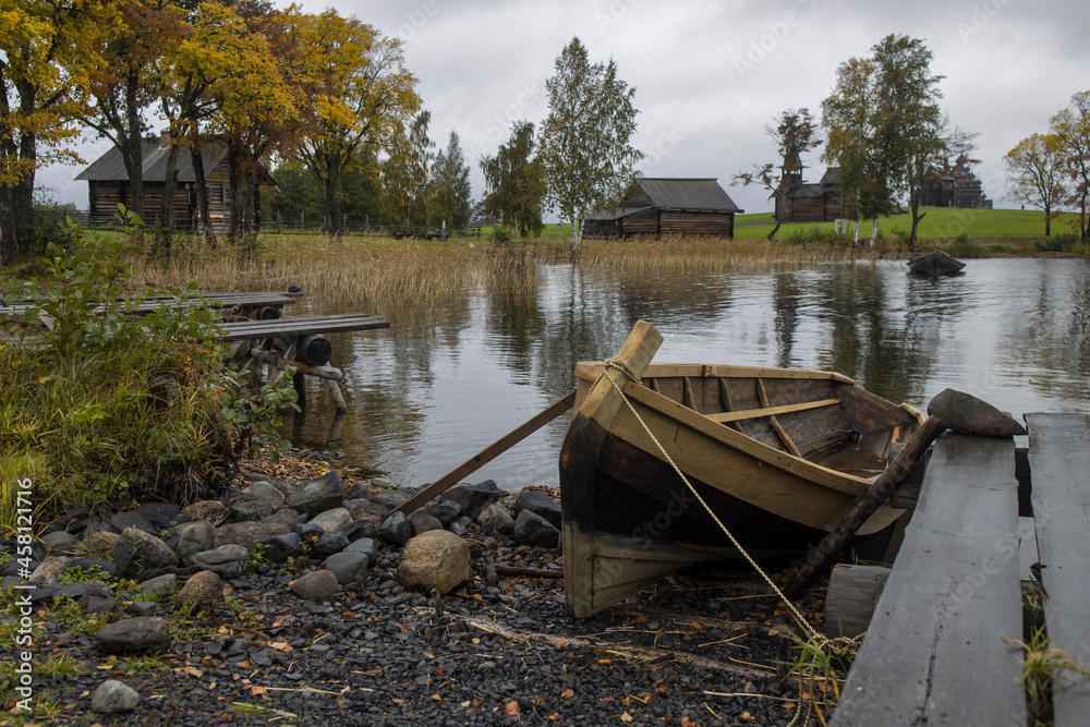 Russia, Republic of Karelia, Kizhi Island: Old traditional wooden boat at riverside of Lake Onega with Transfiguration Church on Kizhi Pogost, a historical site and Russian national open air museum.