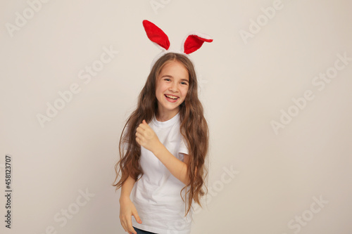 a beautiful girl with long hair in a white Tshirt with rabbit ears smiles Easter