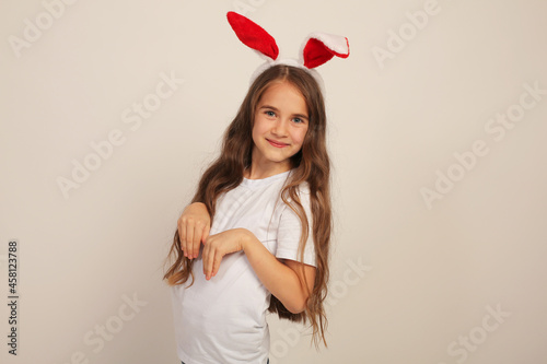 a beautiful girl with long hair in a white Tshirt with rabbit ears smiles Easter