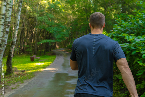 A man athlete runs in the park outdoors, around the forest, oak trees green grass young enduring athletic athlete healthy runner nature, workout young legs male, park wellbeing. cross, stretching