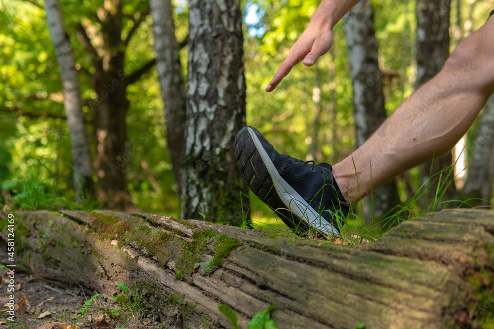 A young enduring athletic athlete is doing stretching in the forest outdoors, around the forest, oak trees. athlete forest, athletic person male, park outside. Summer body cross, runners stretches A young enduring athletic athlete is doing stretching in the forest outdoors, around the forest, oak trees. athlete forest, athletic person male, park outside. Summer body cross, runners stretches