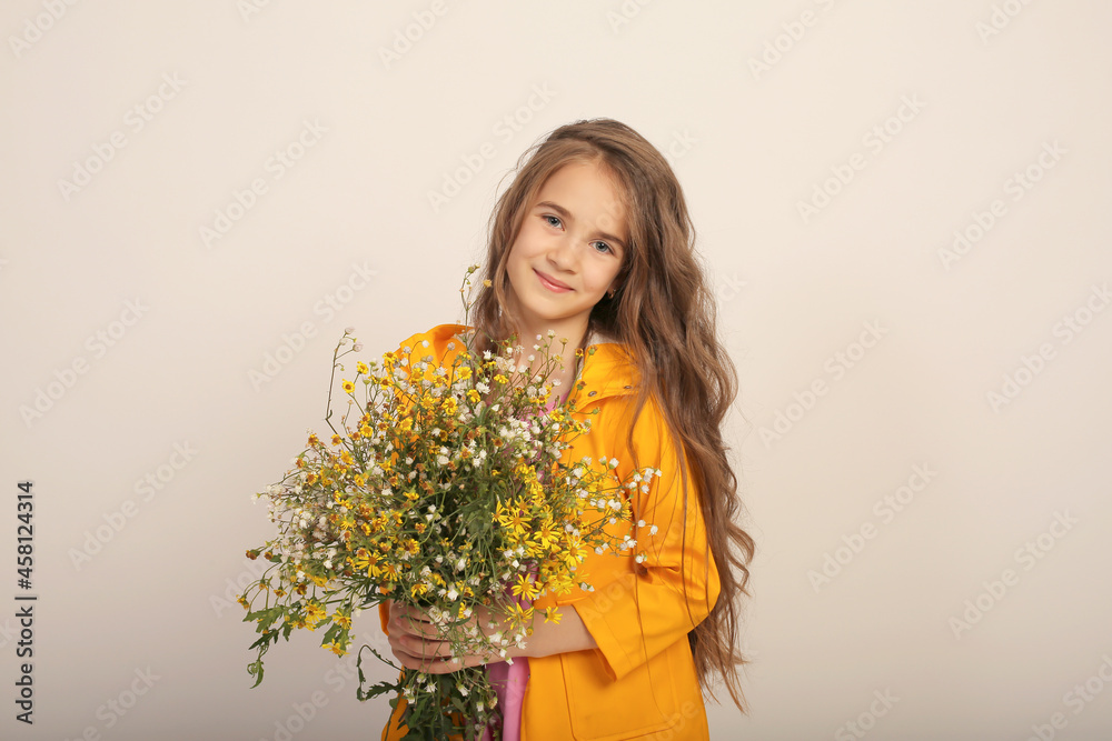 a beautiful long-haired girl in a pink dress and a yellow raincoat with wild autumn flowers in her hands