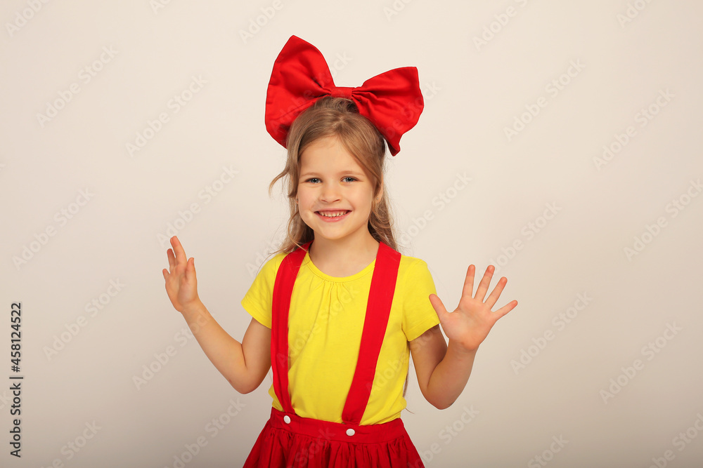 a beautiful happy girl with a red bow on her head in a red skirt in a yellow T-shirt in colored socks a beautiful happy girl with a red bow on her head in a red skirt in a yellow T-shirt in colored socks