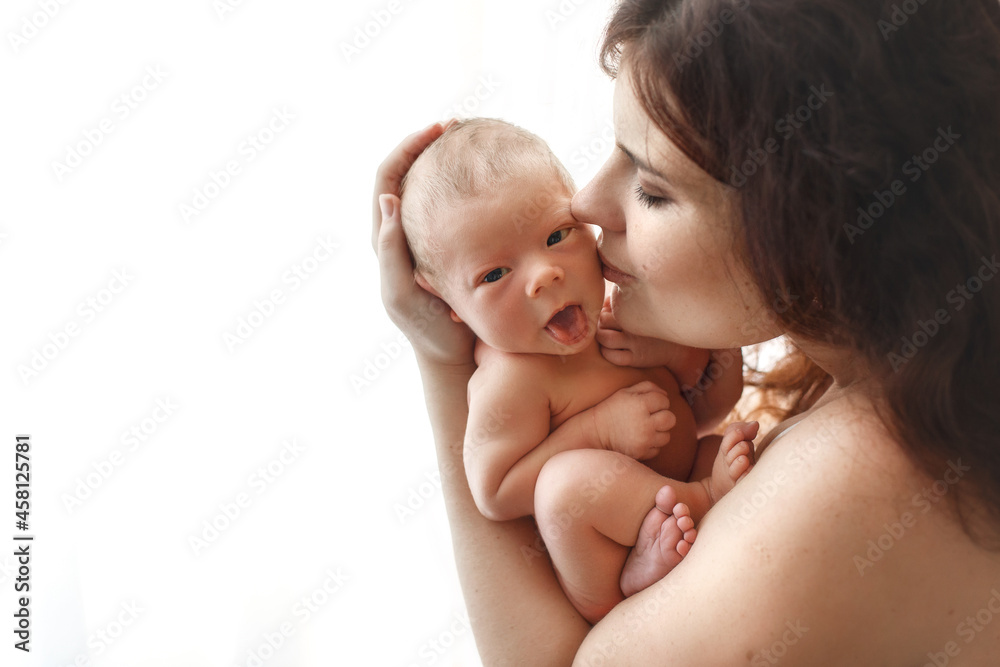 Sleeping newborn baby on the hands of mother. A few days from birth. White background. Mom kissing her son. Sleeping newborn baby on the hands of mother. A few days from birth. White background. Mom kissing her son.