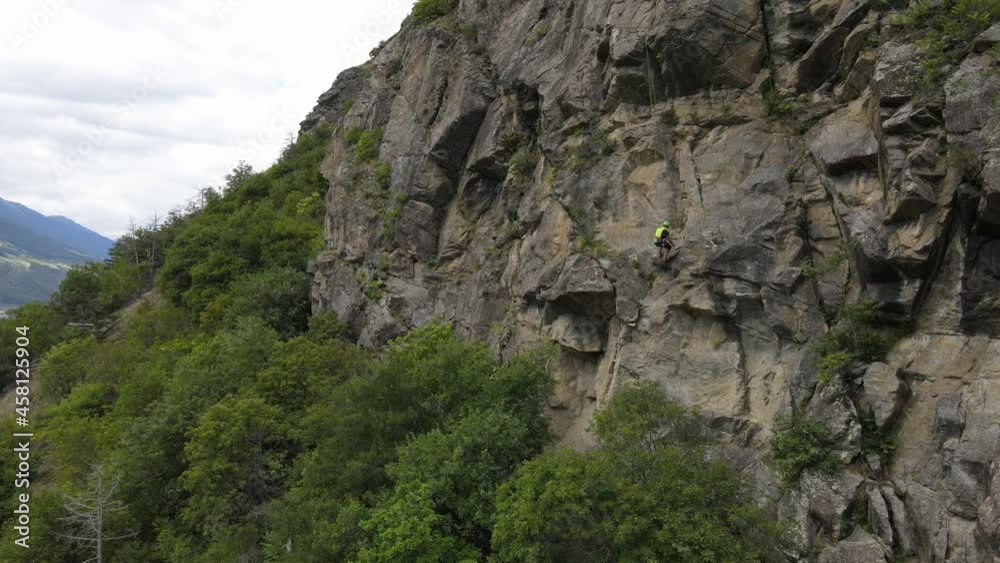 Strong muscular man rock climber, rappels down and removes the quickdraw on the hooks. successful completion of the climbing route. Outdoor rock climbing and active lifestyle concept, drone shot Strong muscular man rock climber, rappels down and removes the quickdraw on the hooks. successful completion of the climbing route. Outdoor rock climbing and active lifestyle concept, drone shot