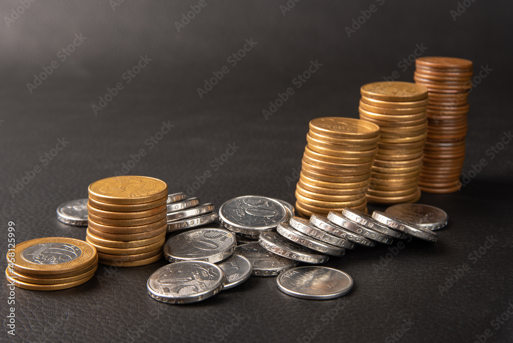 Coins, Brazilian coins of various values stacked on black leather, selective focus. Coins, Brazilian coins of various values stacked on black leather, selective focus.
