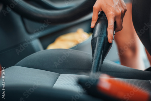 Mujer joven aspirando el asiento del vehículo en un lavadero de coches