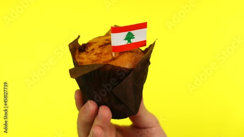 Cupcake with Lebanese flag on male palm against yellow background