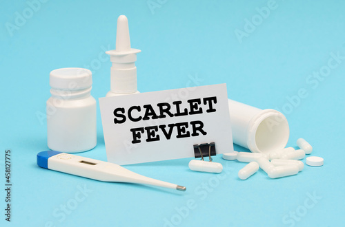 On a blue background, a thermometer, pills and a business card with the inscription - Scarlet Fever photo