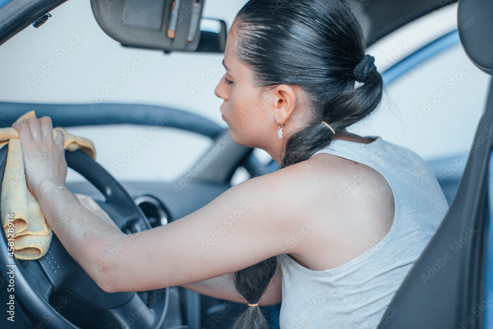 Mujer comprometida y entusiasmada lavando el volante con un paño de limpieza el interior del vehículo en un túnel de lavado para coches Mujer comprometida y entusiasmada lavando el volante con un paño de limpieza el interior del vehículo en un túnel de lavado para coches