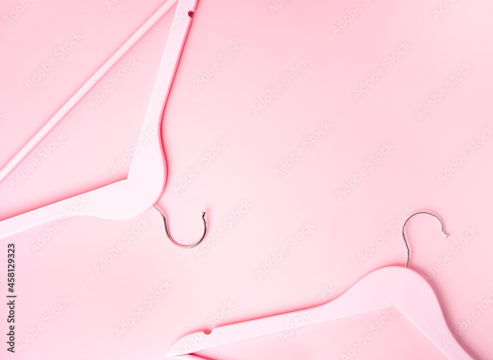 Pink wooden hangers on a pastel pink background. Geometric composition with space for text, top view. The concept of sale, black Friday, conscious consumption in the fashion industry.