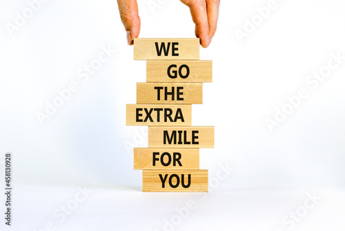 Go the extra mile symbol. Wooden blocks with words 'We go the extra mile for you'. Businessman hand. Beautiful white background. Business and go the extra mile concept. Copy space.