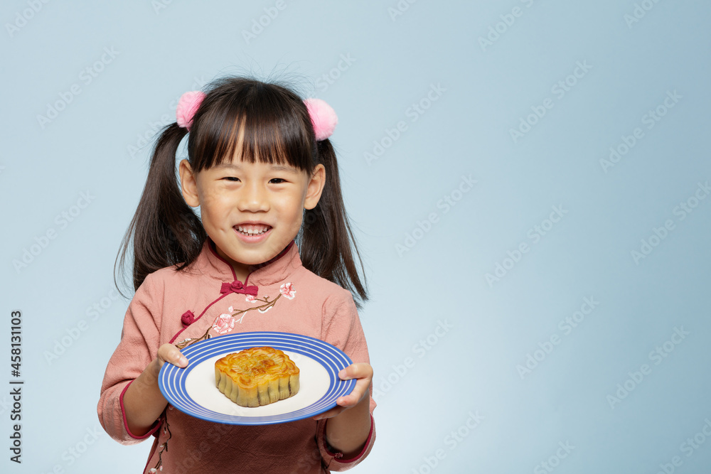 young girl holding traditional Chinese moon cake against plain blue background young girl holding traditional Chinese moon cake against plain blue background