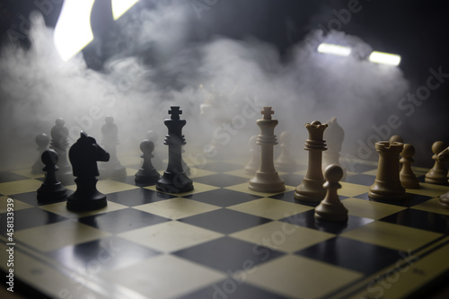 chess board game concept of business ideas and competition and strategy ideas concep. Chess figures on a dark background with smoke and fog and window with sunlight. Selective focus