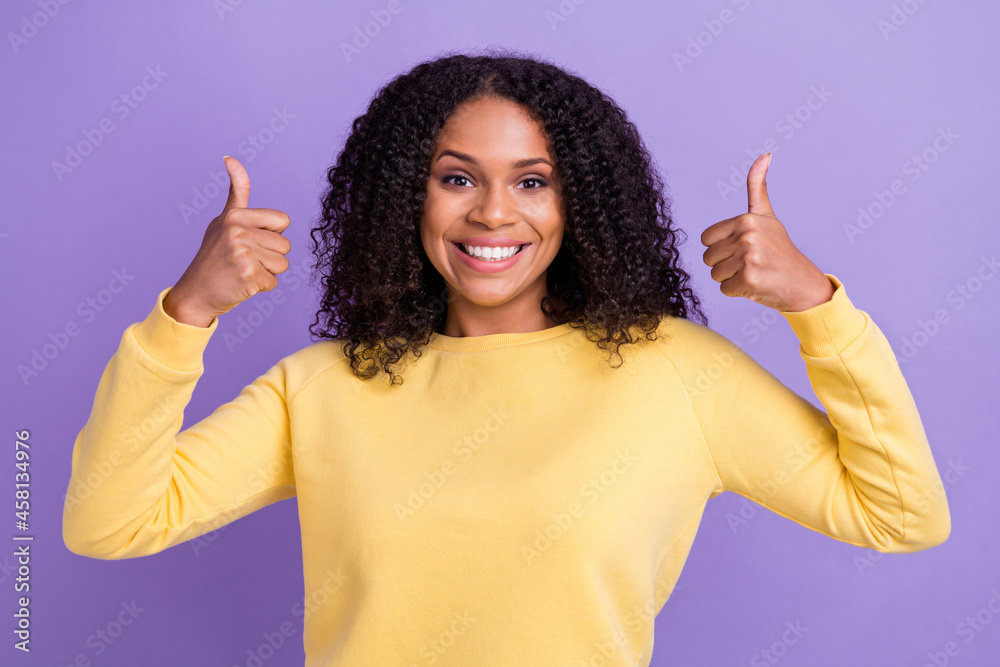 Photo of cute adorable dark skin lady wear yellow pullover showing two thumbs up smiling isolated purple color background Photo of cute adorable dark skin lady wear yellow pullover showing two thumbs up smiling isolated purple color background