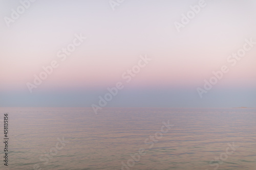 Peaceful sunset at the ocean. Pastel pink gradient from water to sky. Abstract minimalist background. Summer, vacation, tranquility concept