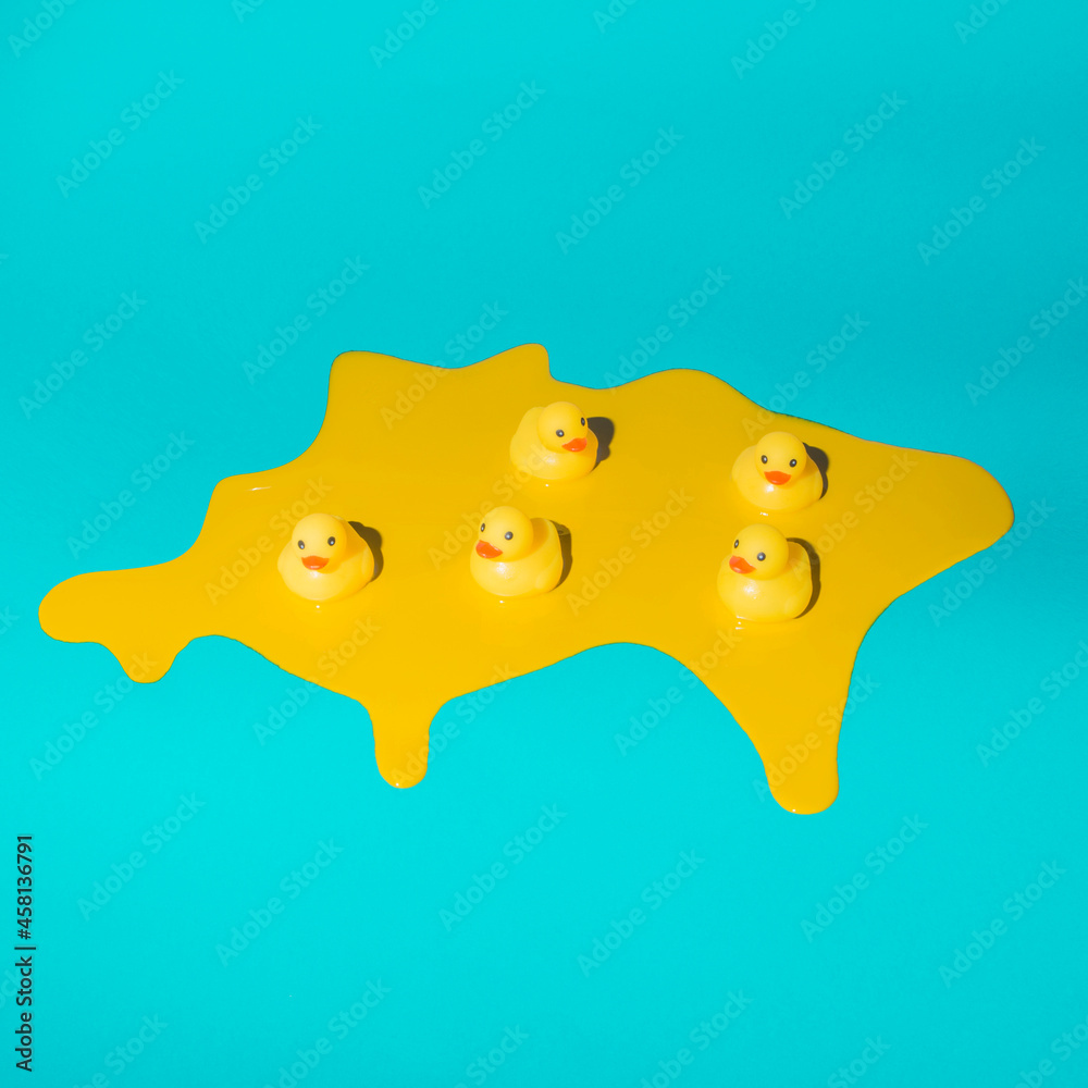 Five rubber ducklings swimming in melted yellow paint on trendy blue background. Minimal abstract season, environment or fashion concept. Flat lay with copy space. Five rubber ducklings swimming in melted yellow paint on trendy blue background. Minimal abstract season, environment or fashion concept. Flat lay with copy space.