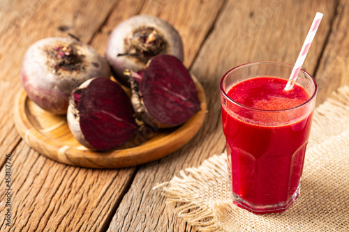 Red beet juice in a glass cup on the wooden table.
