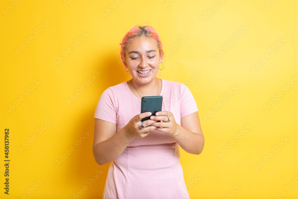 Fototapeta premium Young Mexican student smiling using cell phone. Hispanic sending messages