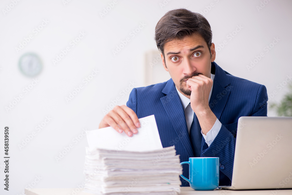 Young male employee and too much work in the office Young male employee and too much work in the office