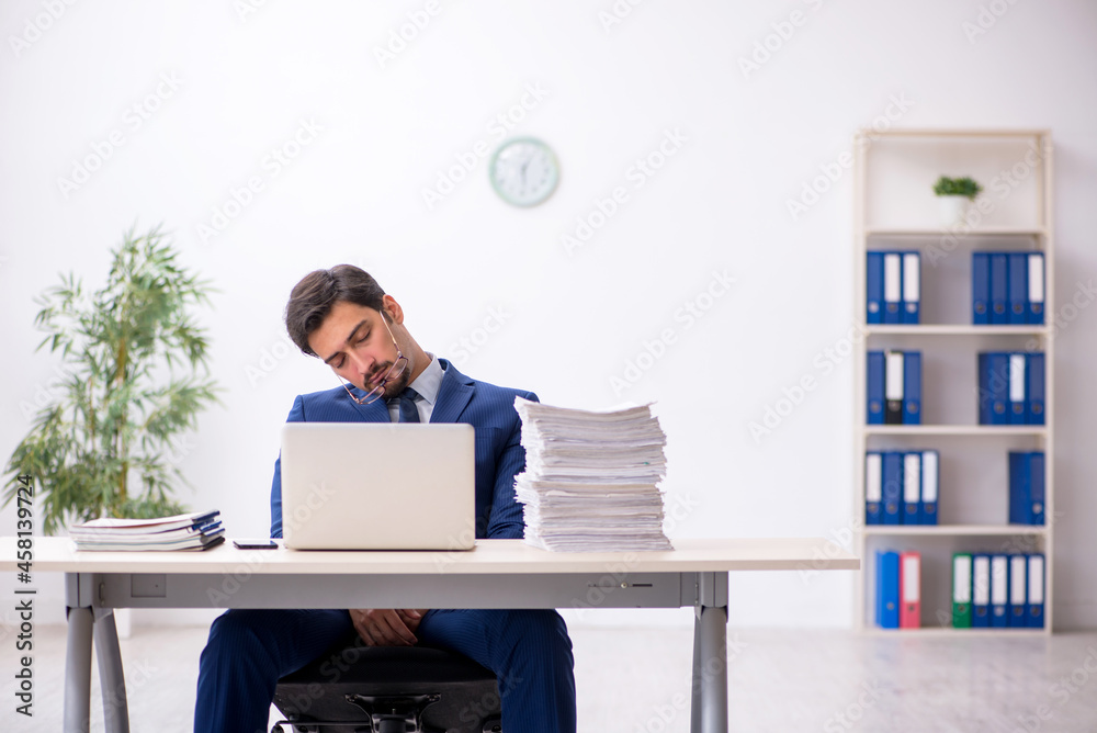Young male employee and too much work in the office Young male employee and too much work in the office