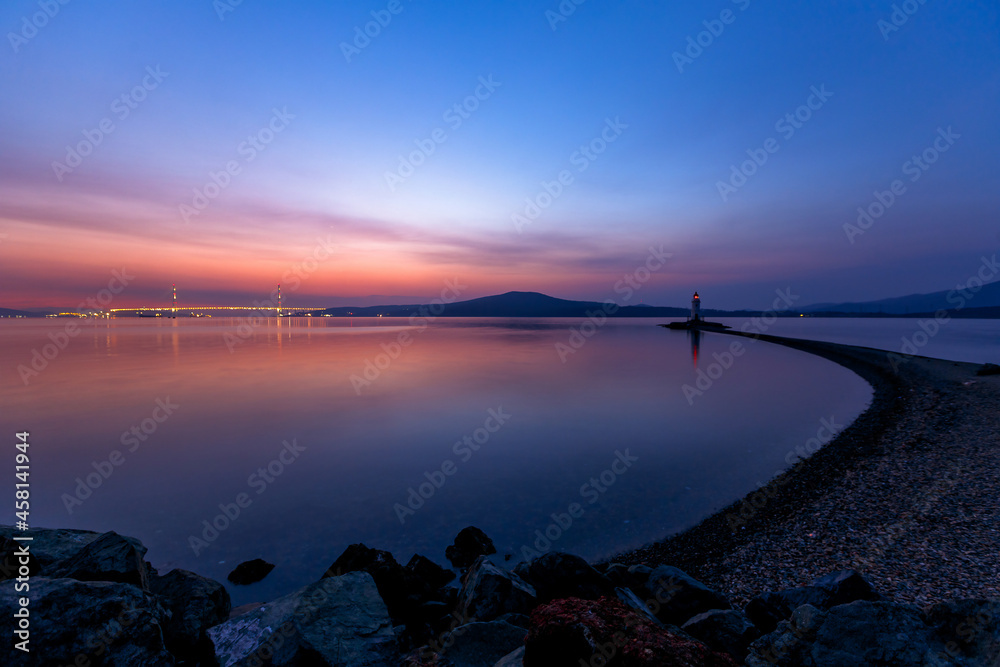 The Tokarevsky lighthouse in Vladivostok stands on a deserted spit. Bright sunrise in the sea capital of the Far East.