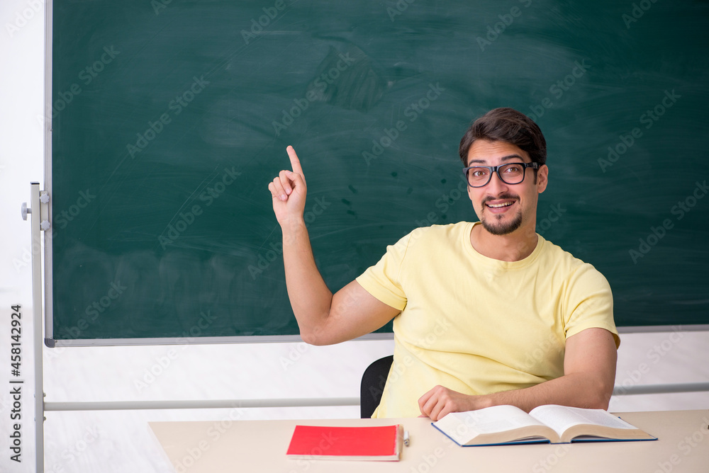 Young male student in front of blackboard Young male student in front of blackboard