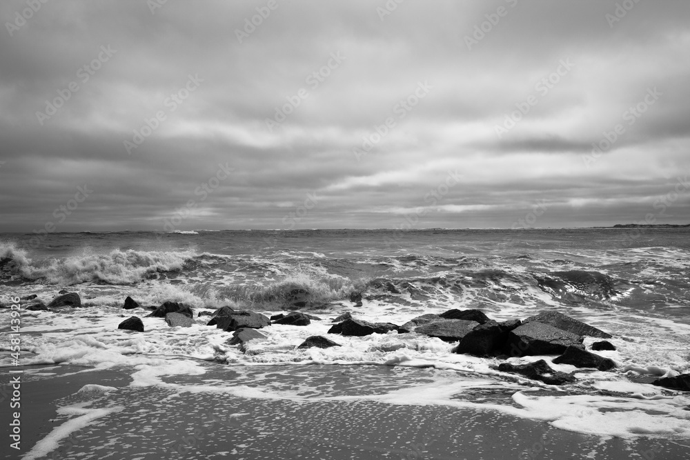 Black and white photo at Vilano Beach, Florida with rocks on the shoreline and whitecaps on the waves