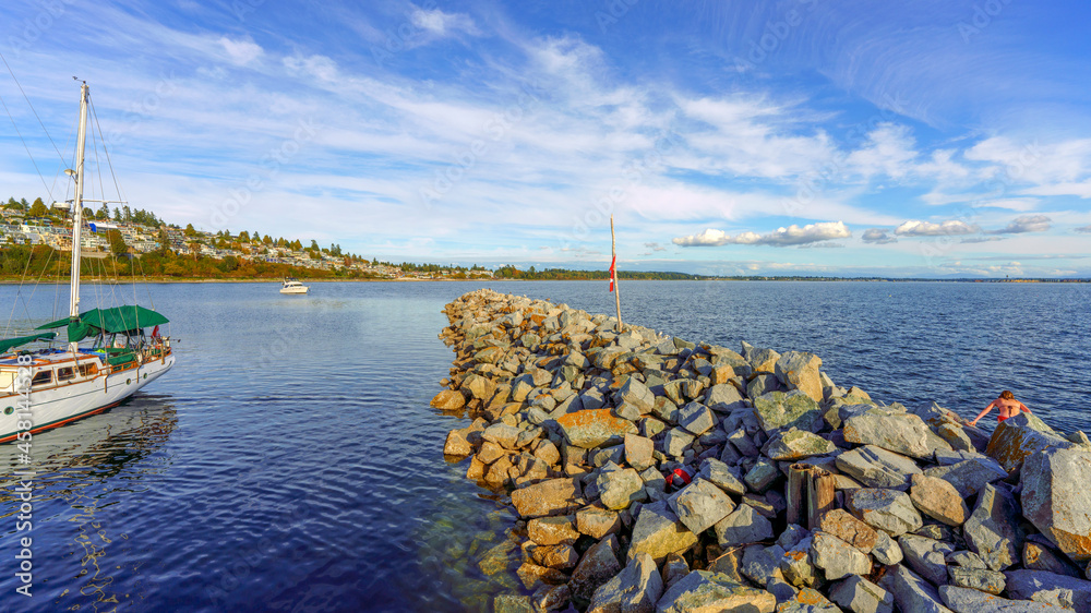 Rock breakwater and private watercraft at Boundary Bay as seen from White Rock Pier on an end-of-summer afternoon, with views to White Rock water view residences