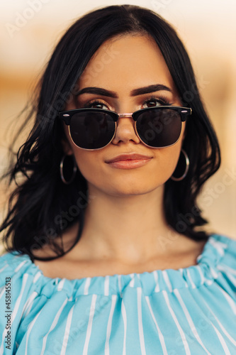Portrait of a beautiful young brunette woman in sunglasses smiling