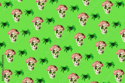 Skull mask with flowers and spiders against green background. Halloween or Santa Muerte concept.