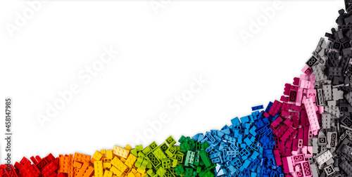 top view of wide pile various colorful rainbow colored stackable plastic toy bricks isolated white panorama background.. childhood education construction concept photo