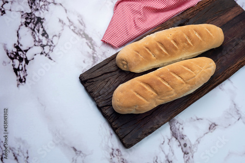 Whole and sliced long homemade bread on natural and fresh wooden board