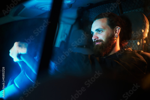 Confident bearded man driving inside his vehicle at night