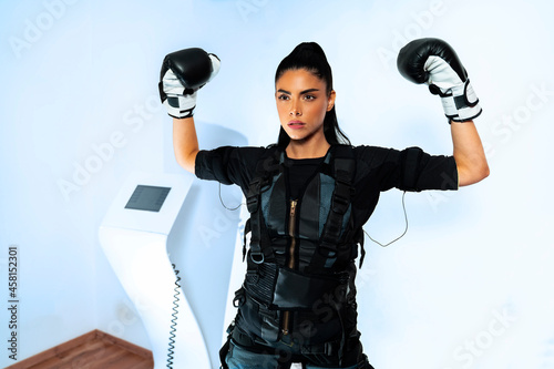 Attractive female with boxing gloves attached to EMS training machine  photo