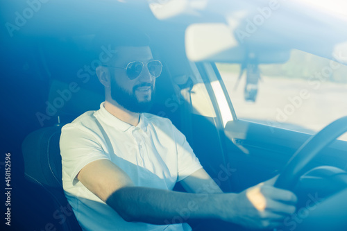 Young business man sitting in car holding steering wheel follows the road