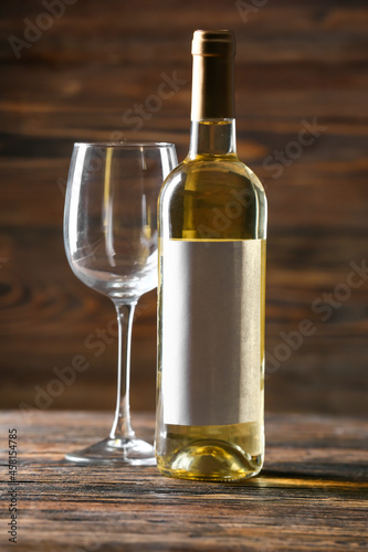 Bottle of delicious wine and glass on wooden background
