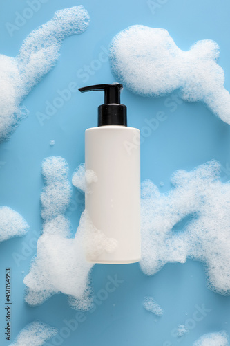 Bottle of cosmetic product with foam on color background photo