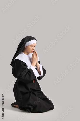 Young praying nun on grey background photo