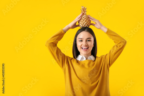 Beautiful young woman with decorative pineapple on yellow background © Pixel-Shot