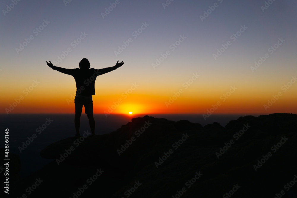 Victorious Silhouette On Mountain Peak At Colorful Sunrise With Arms Out