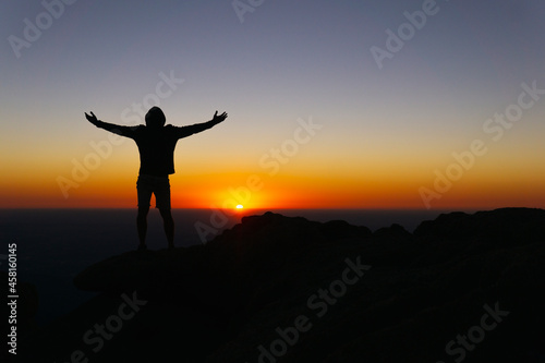 Victorious Silhouette On Mountain Peak At Colorful Sunrise With Arms Out