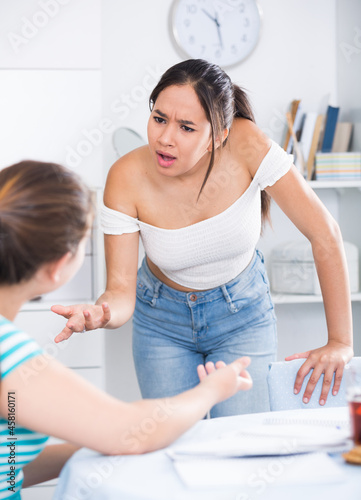 Quarrel between two teens girls friends in home interior