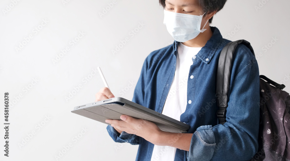 Young asian campus student man wearing protection mask while online study by digital tablet in campus, coronavirus prevention in university, social distancing, online learning Young asian campus student man wearing protection mask while online study by digital tablet in campus, coronavirus prevention in university, social distancing, online learning