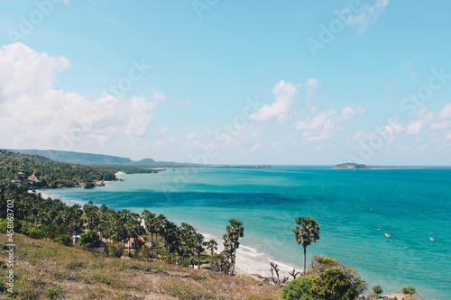 View of Rote Tropical Beach with deep turquoise blue ocean and small exotic island in the center in Rote Island, Indonesia.