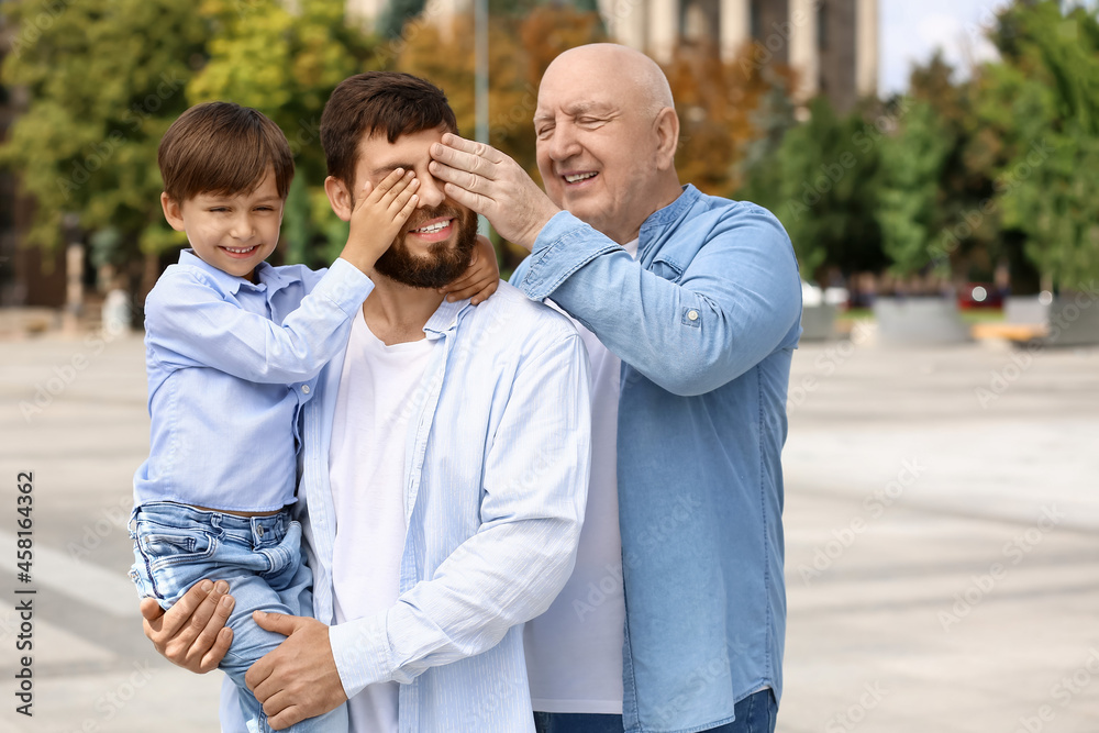 Obraz premium Happy man, his little son and father walking outdoors