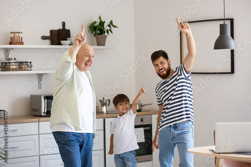 Happy man, his little son and father dancing in kitchen