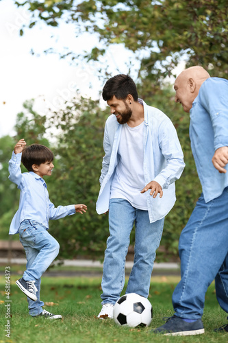Man, his little son and father playing football in park
