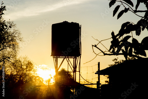 Silhouette of a rain water tank on a stand at sunset photo