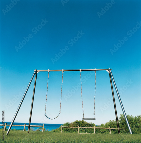 Playground swing set with blue sky and ocean background photo